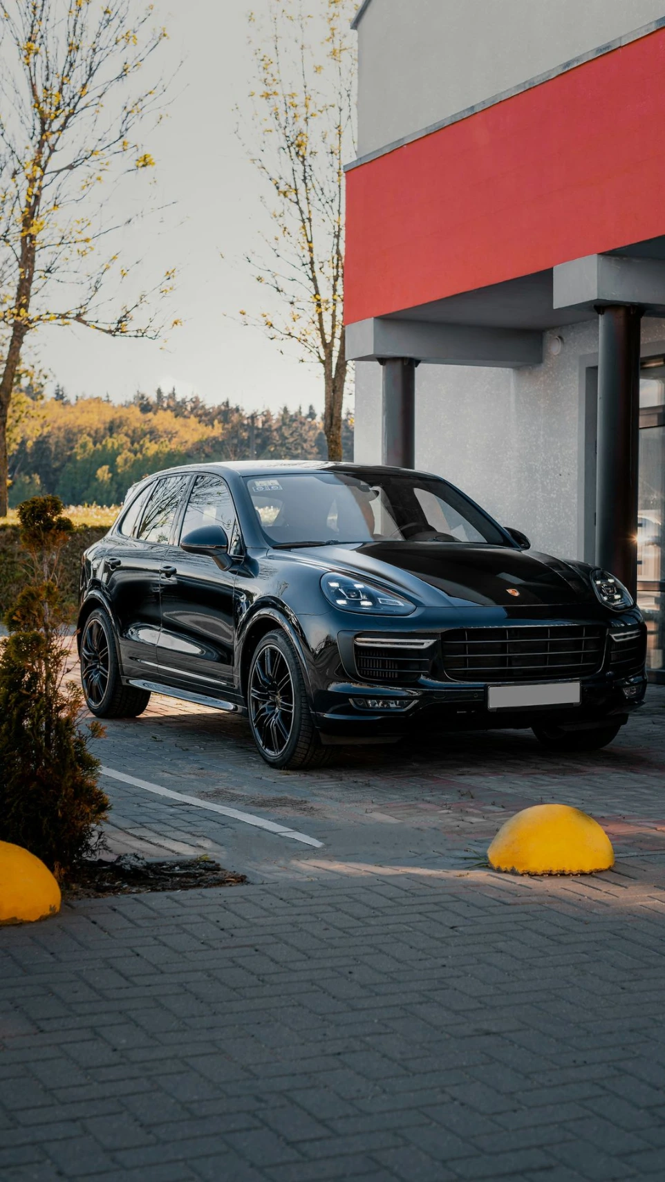 a black porsche cayen parked in front of a building